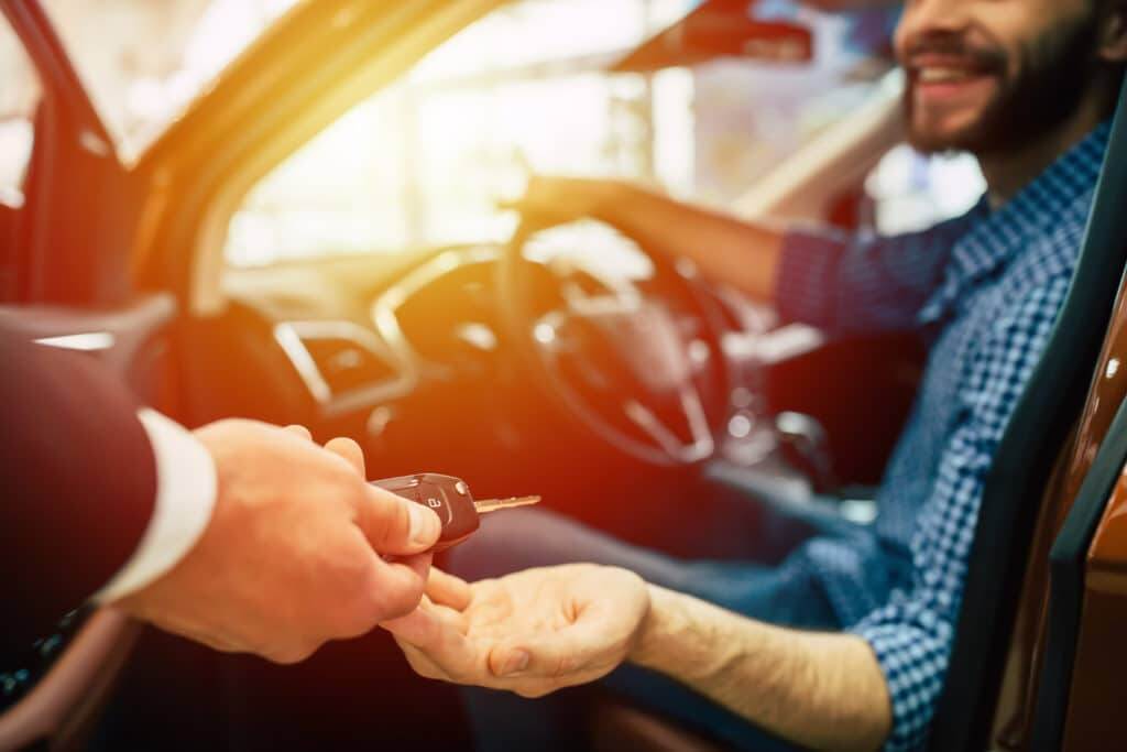 Man in drivers seat being handed keys