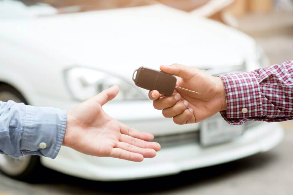 car shipping close-up picture of two male hands transferring a single car key