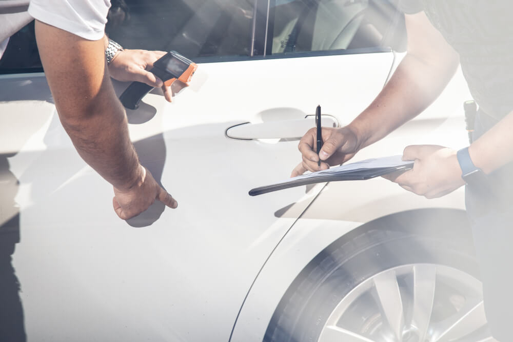 Inspectors review vehicle damage. Auto transport.