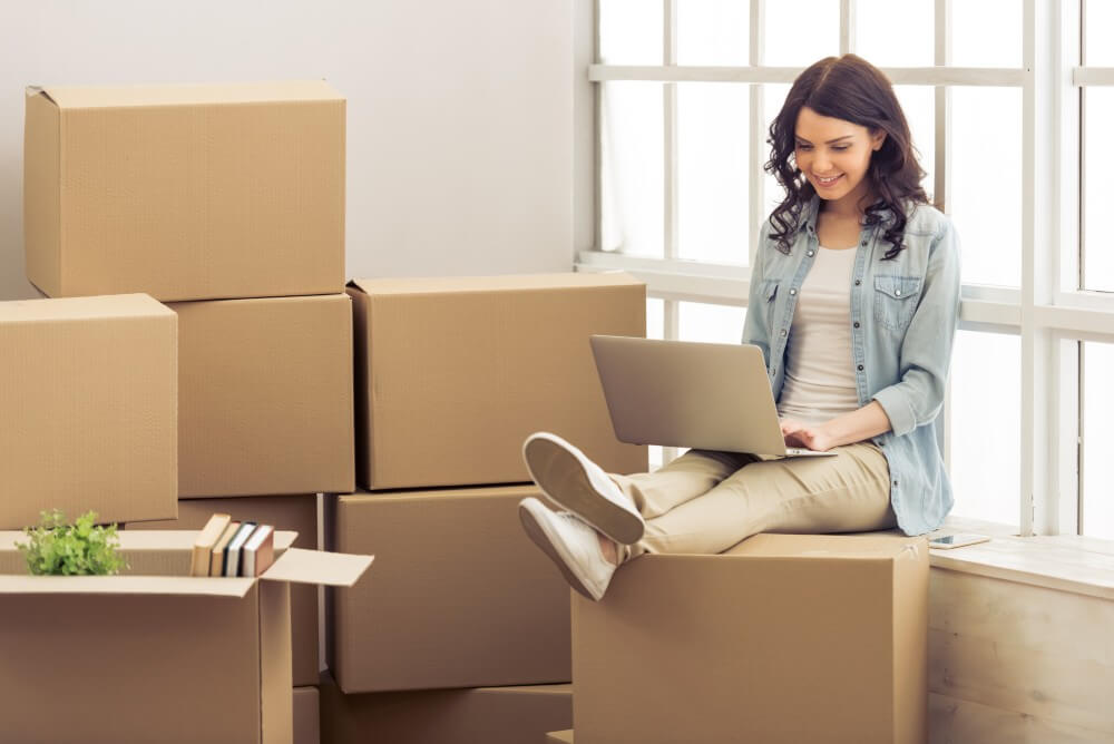 Woman sitting on packed boxes.