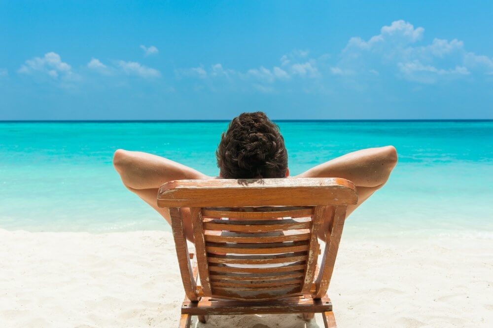 Man relaxing on a beach with an ocean view. Ship a car to another state.