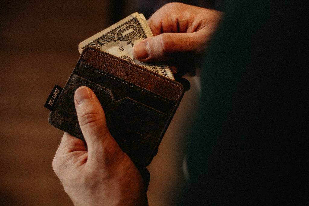 A wallet with the owner pulling money out of it. auto transport nationwide.