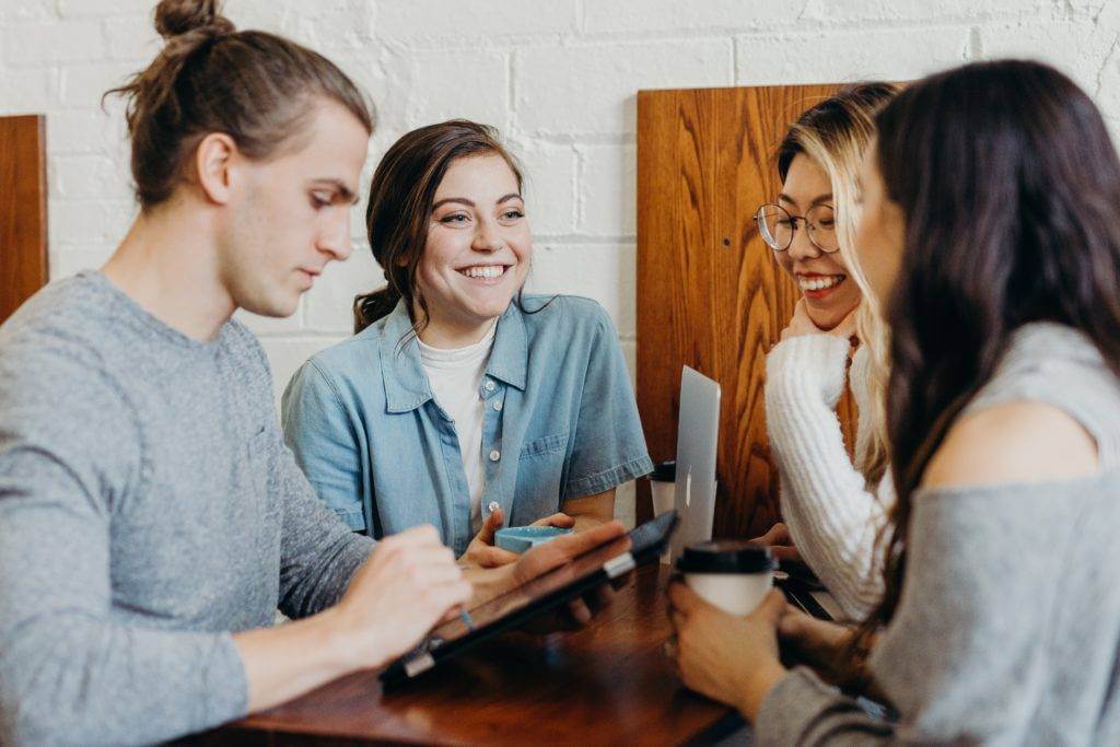 A group of friends in discussion at a coffee shop. Go with enclosed car transport companies.