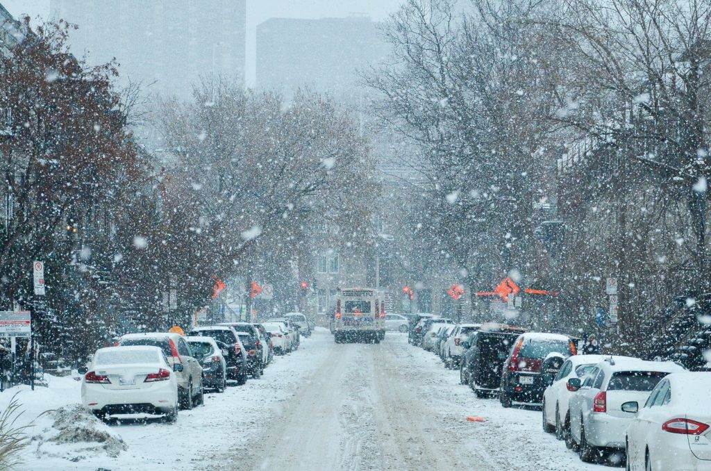 Street with parked car and heavy snow fall. cheaper auto transport.