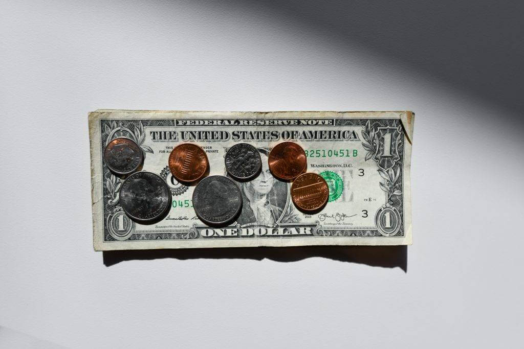A single dollar bill laying flat with 73 cents on top. Car shipping in Hawaii.