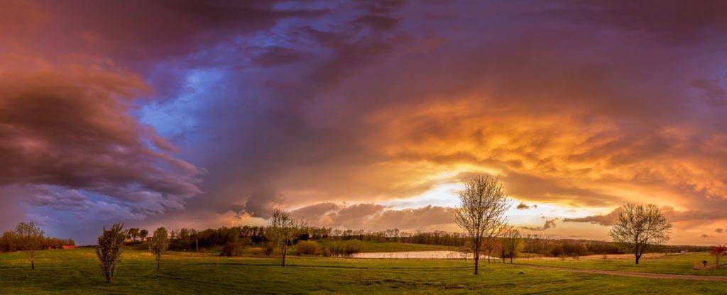 A scenic view of a country hill side with the cloud cover and the sun setting. We offer cross country car transport. How Much Does it Cost to Ship a Car?
