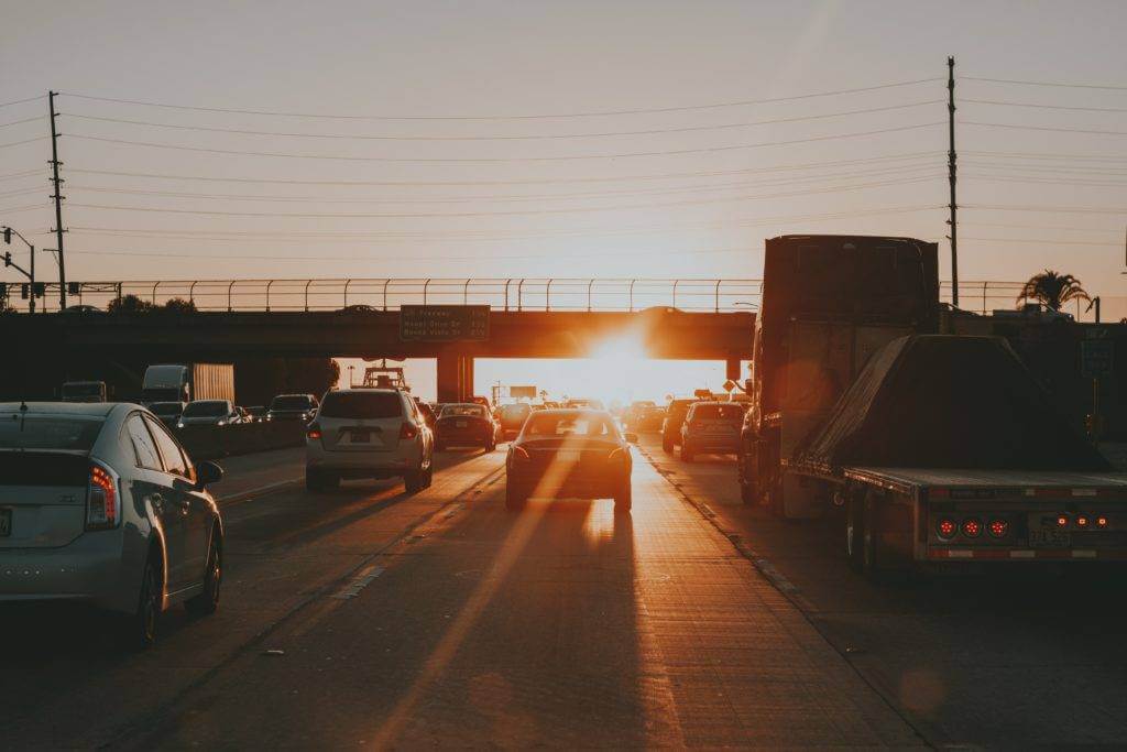 A view from the middle of a city highway with the sun setting. Enclosed auto transport. Open auto transport.
