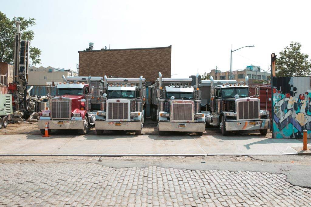 Four Semi-Trucks were parked in a parking lot. The best car shipping companies have access to 10s of thousands of truck drivers to service all 50 states.