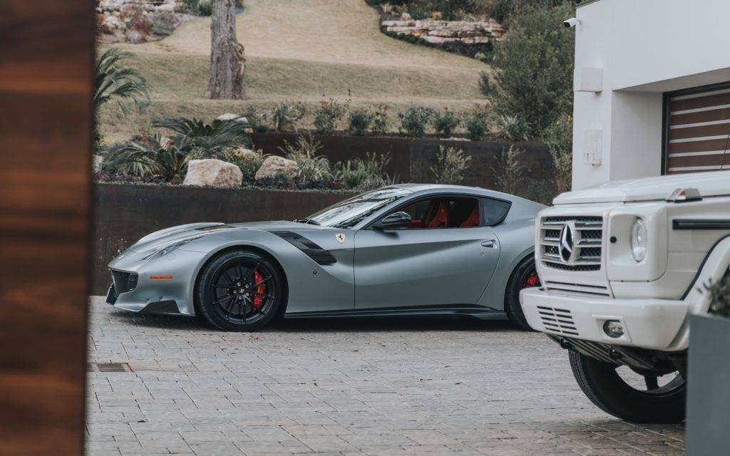A Ferrari and Mercedes Benz G wagon parked in the front of a garage. Luxury Auto Transport.