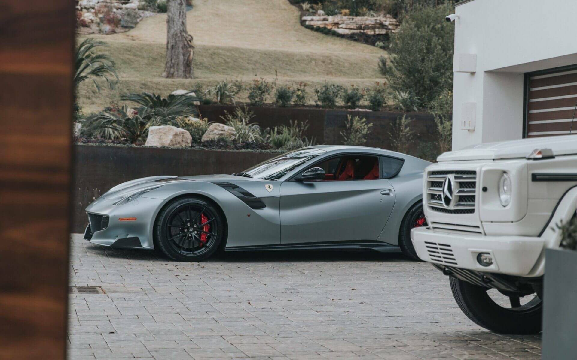 A Ferrari and Mercedes Benz G wagon parked in the front of a garage. Luxury Auto Transport.
