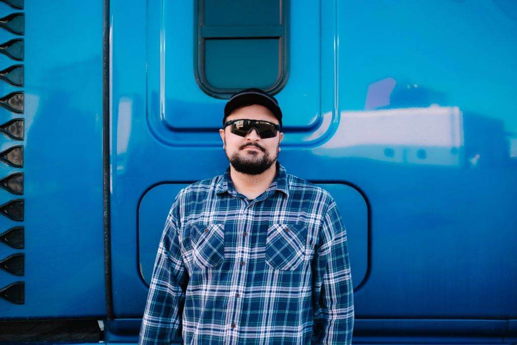A truck driver standing outside of his Semi-Truck cabin. Vehicle transport company with National Transport Services are the professionals in the auto transport industry.