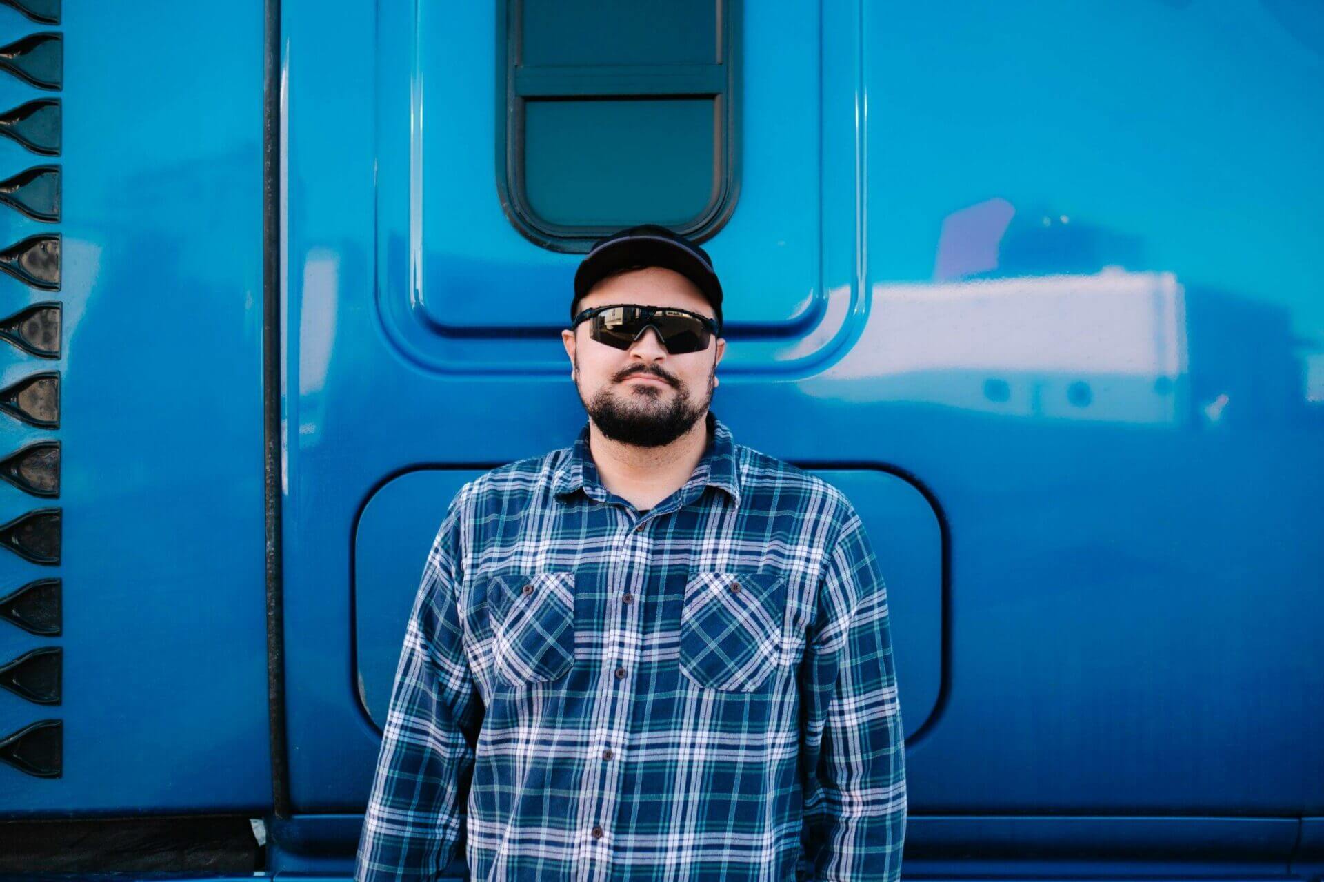A truck driver standing outside of his Semi-Truck cabin. Vehicle transport company with National Transport Services are the professionals in the auto transport industry.