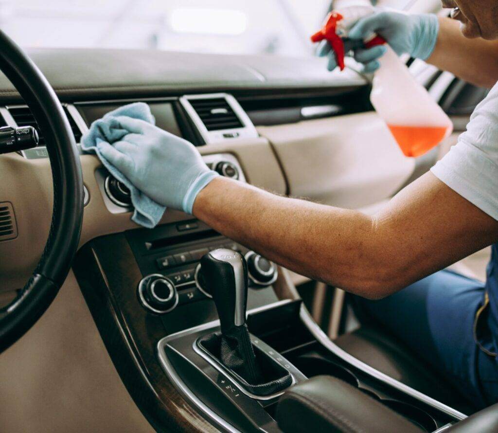 Man cleaning the inside of his car before the long-distance car towing company arrives. Long-distance car transportation is surprisingly easy and safe. Local tow truck services are extremely expensive compared to an auto transport company. So if you want to get your long-distance towing cost down, contact us today.