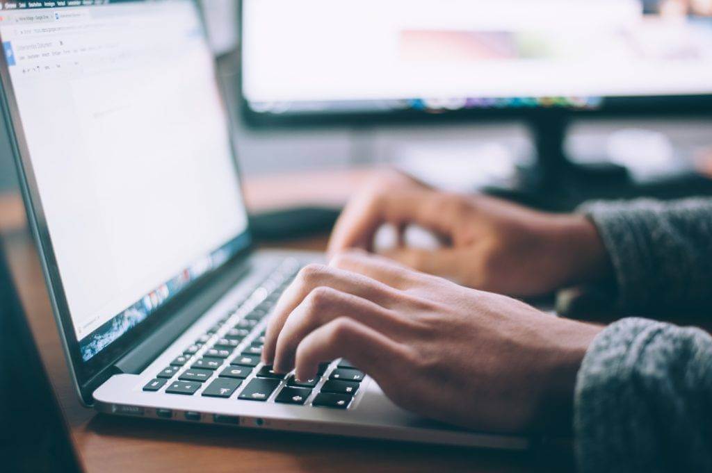 Hands typing on a laptop computer. Do your research on each and every motor carrier.
