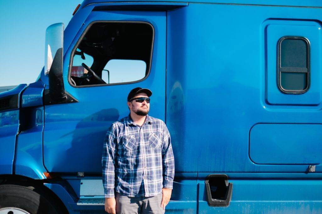Truck driver standing outside of his truck.