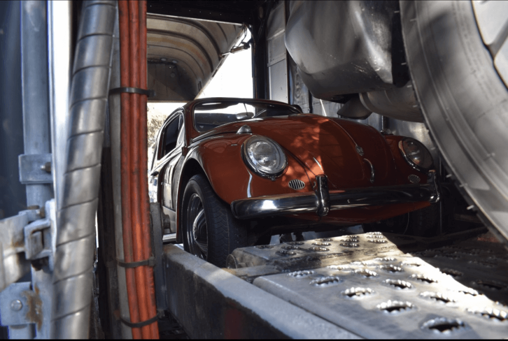 A brown 1960 Volkswagen Beetle that is inside a soft-side enclosed transport trailer. Whether you need to transport a classic car, an exotic car, or your daily driver, enclosed car shipping is for everyone.