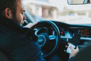 A man is looking at his phone while driving.