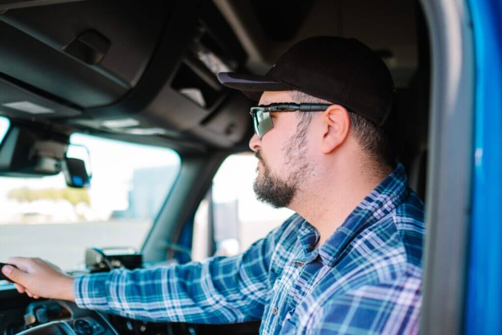A truck driver is driving his semi-truck.