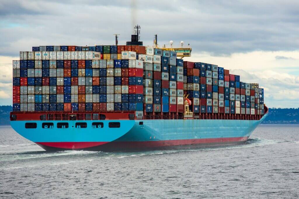 A shipping vessel sailing from port loaded with shipping containers.