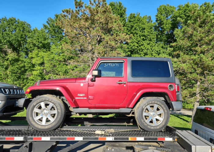 A two-door Jeep Wrangler on an open 3-car wedge trailer.